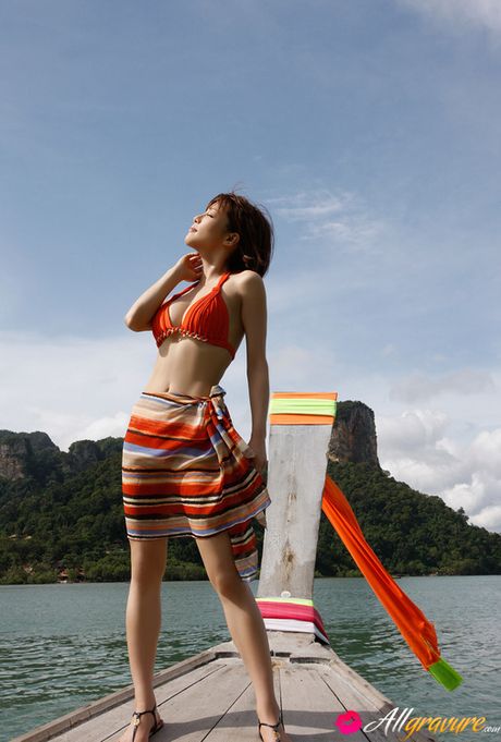 Yumiko Shaku Asian in orange bath suit takes a walk on the beach