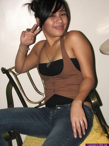 Asian teen with a tiny tattoo on her ass strips and demonstrates her pierced pussy